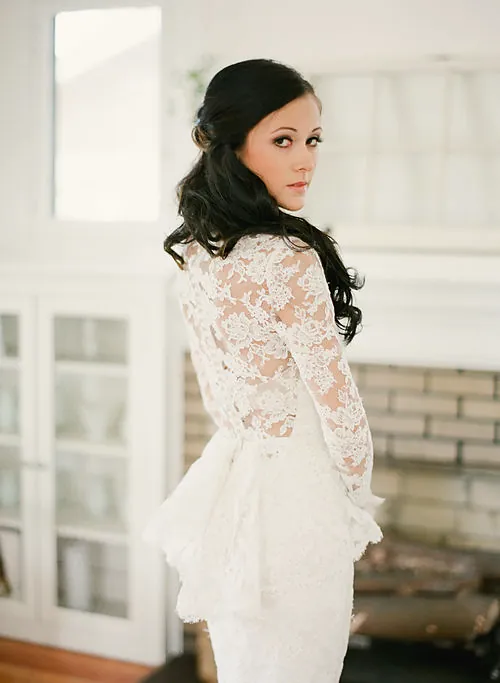 Bride holding a bouquet in lace sleeves