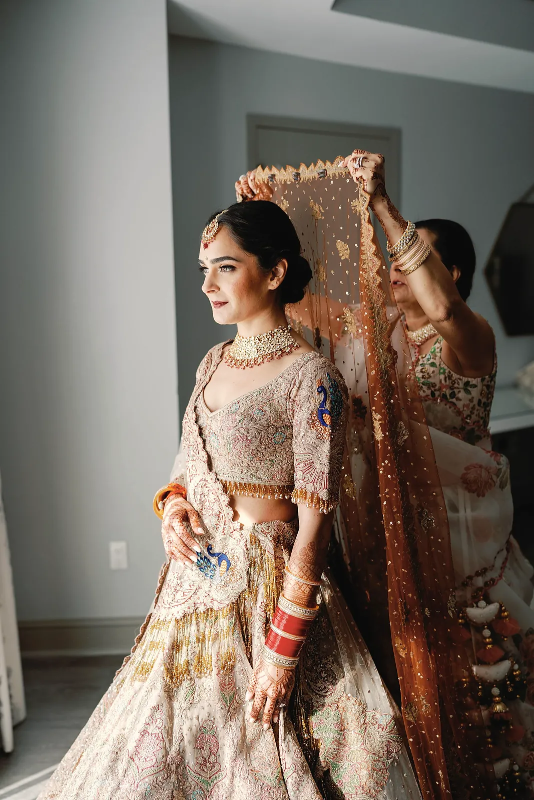 South Asian bride in an embroidered lehenga by a window