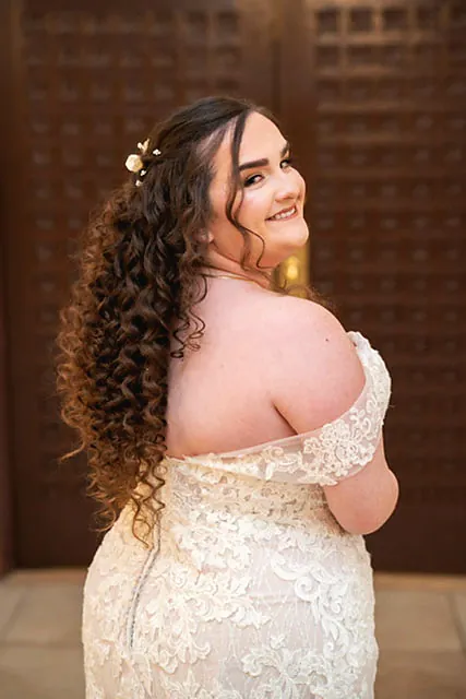 Curly-haired bride in an off-shoulder gown