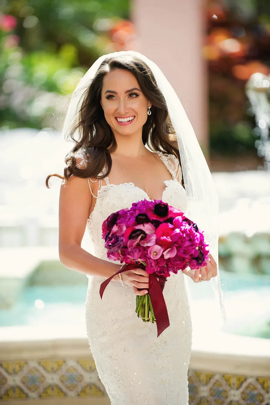 Bride with a magenta bouquet by a pool