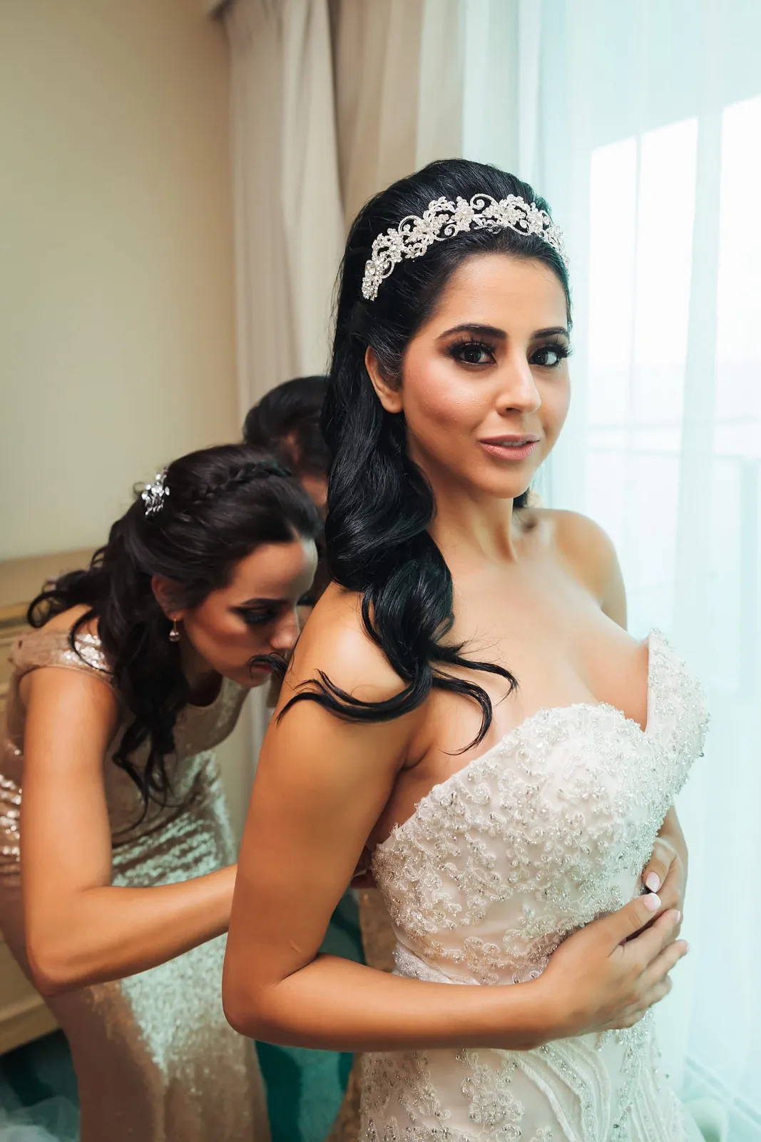 Bride having her veil set by a bridesmaid