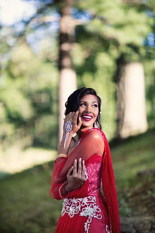 Bride laughing in a red lehenga among the trees